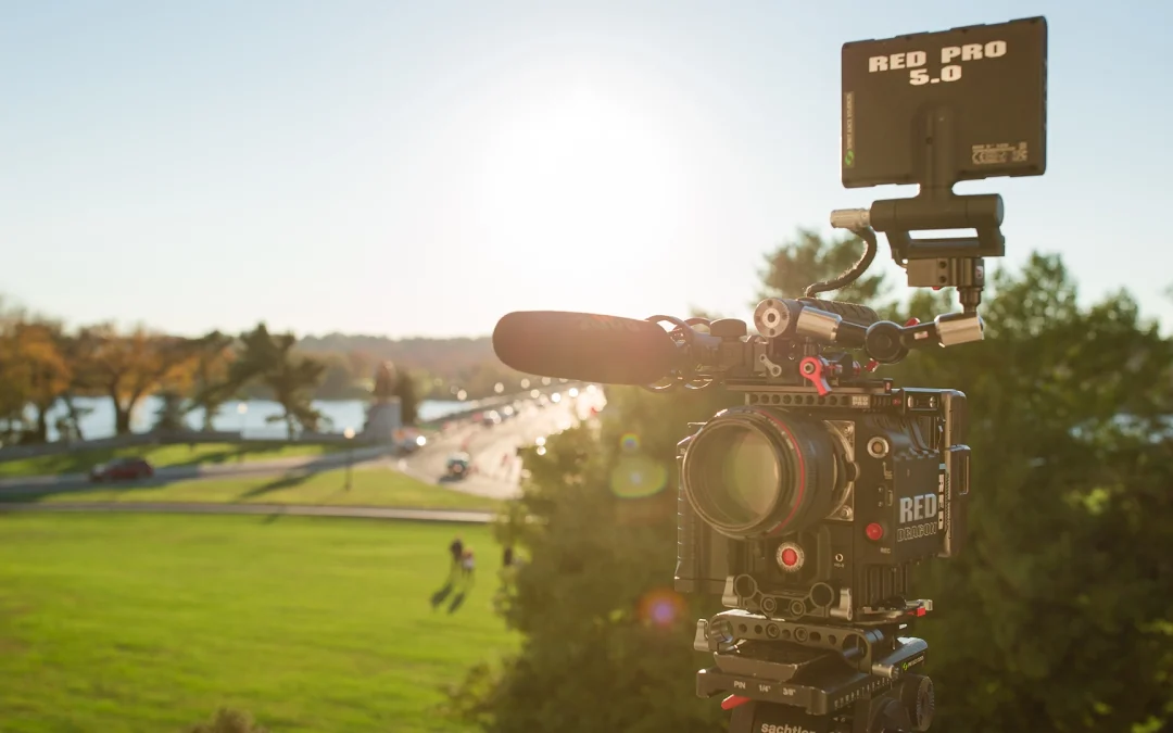 A RED Dragon high-end cinema camera set on a tripod during an outdoor shoot, illustrating professional video production cost and equipment quality.