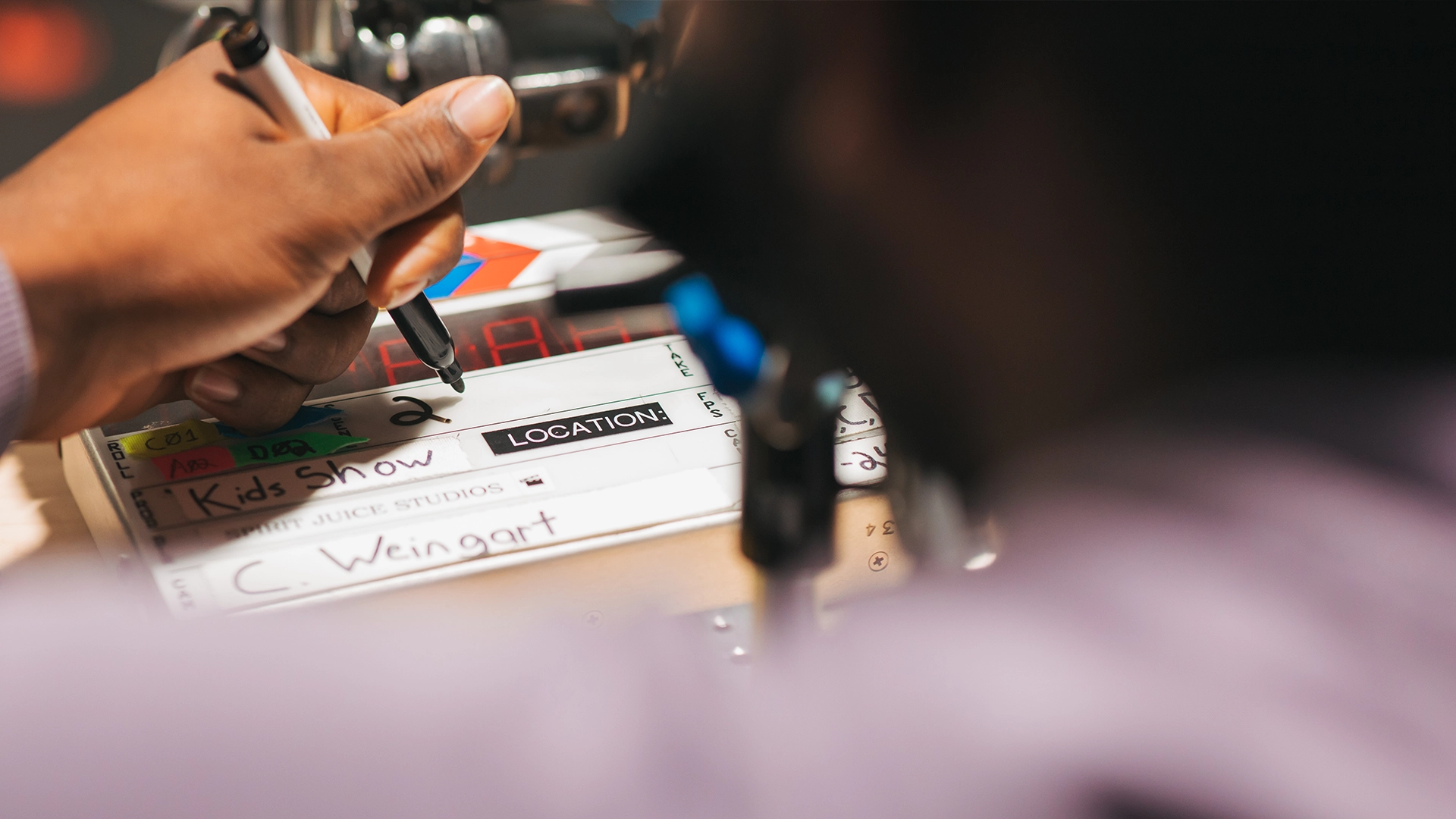 Team members prepare a shoot slate by writing the cast names, scene details, and director information, highlighting an essential step in video pre-production.