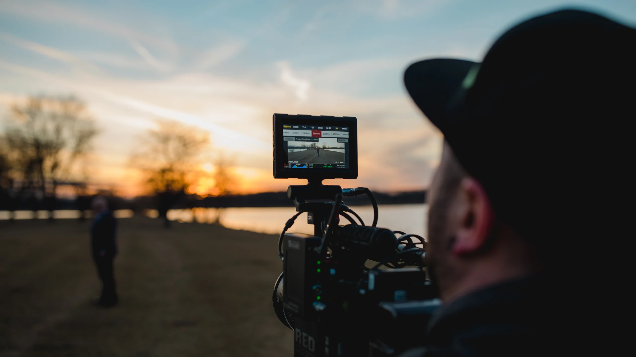 A filmmaker records a priest using a high-end camera, with the camera monitor in sharp focus and the background softly blurred, highlighting the precision of professional video production.