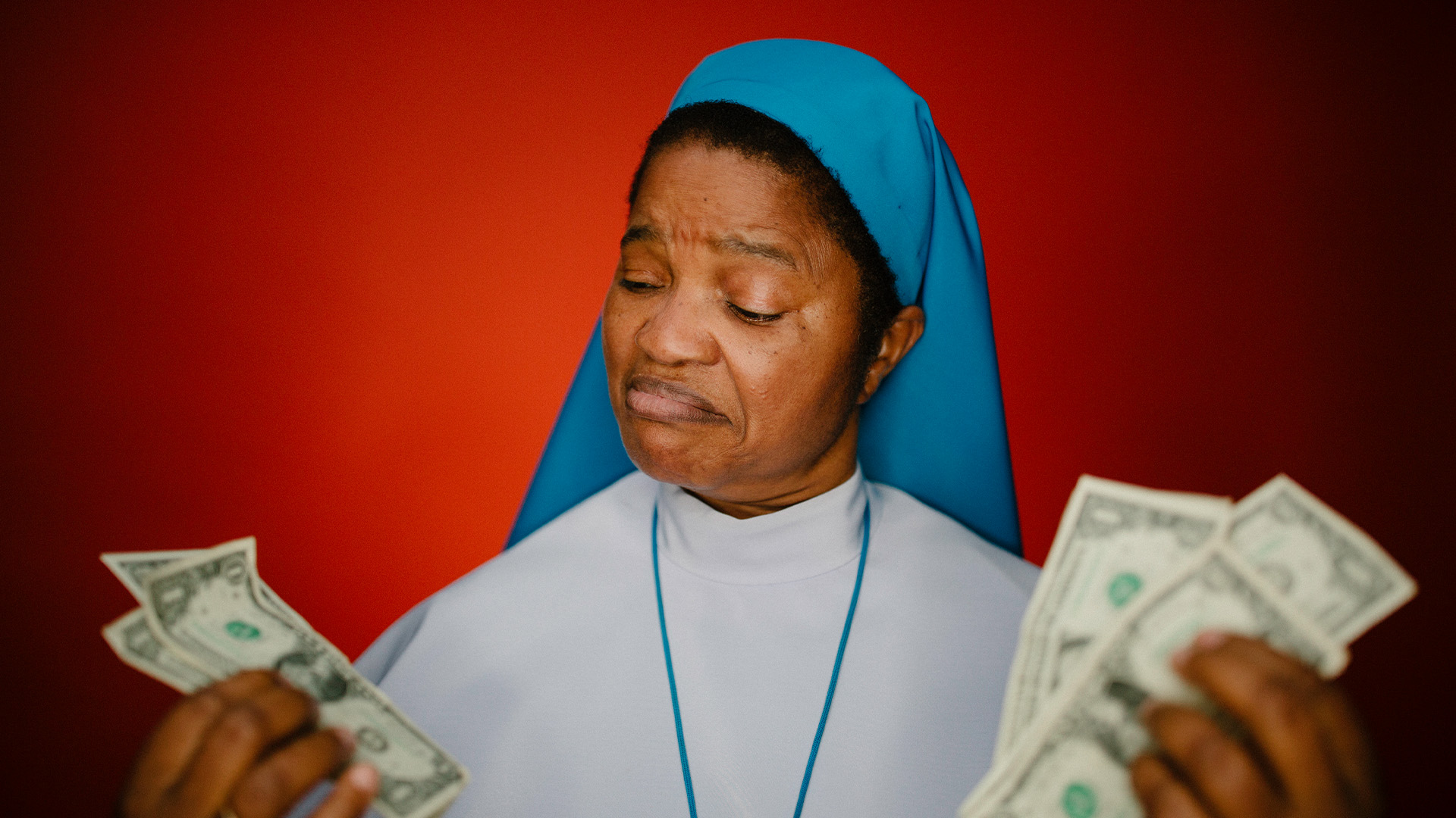 A nun weighs money in both hands with a thoughtful expression, illustrating the question of video production cost vs value and whether a higher video production cost really means a better video.